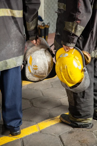 Baixa seção de bombeiros segurando capacetes — Fotografia de Stock