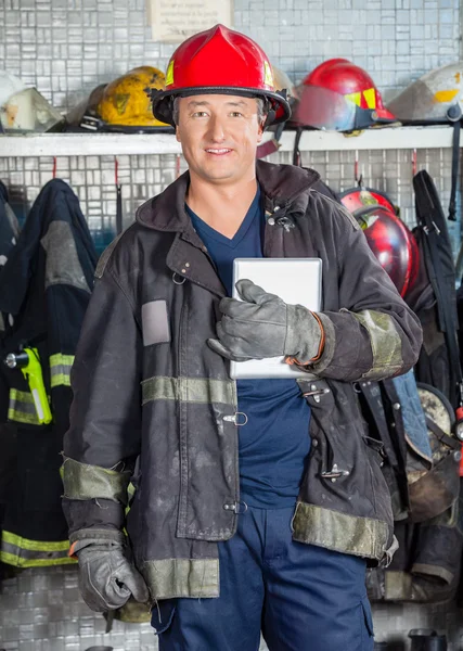 Улыбающийся рабочий держит планшет на пожарной станции — стоковое фото