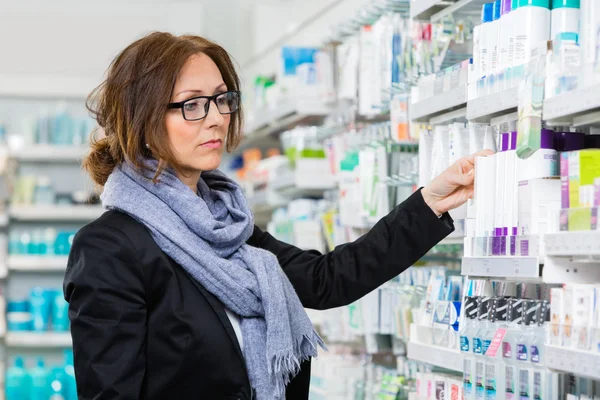 Consumidor femenino eligiendo el producto en farmacia —  Fotos de Stock