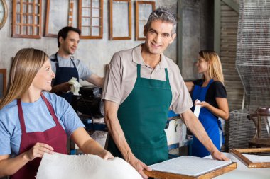 Gülümseyen adam kağıtları meslektaşları ile fabrikada yapım