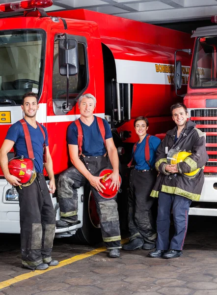 Pompiers confiants s'appuyant sur des camions — Photo