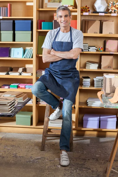 Selbstbewusster Verkäufer mit verschränkten Armen in Buchhandlung — Stockfoto