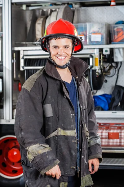 Glücklicher Feuerwehrmann steht gegen LKW — Stockfoto