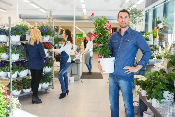 Jistý muž, který držel květ rostlin v obchodě — Stock fotografie