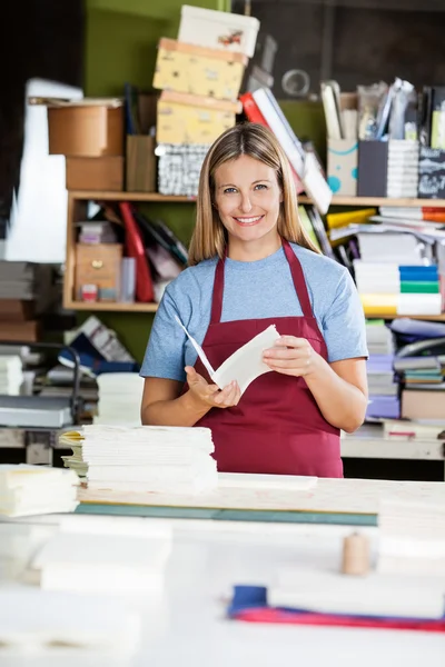 Arbeiterin hält Papier, während sie Notizblock macht — Stockfoto