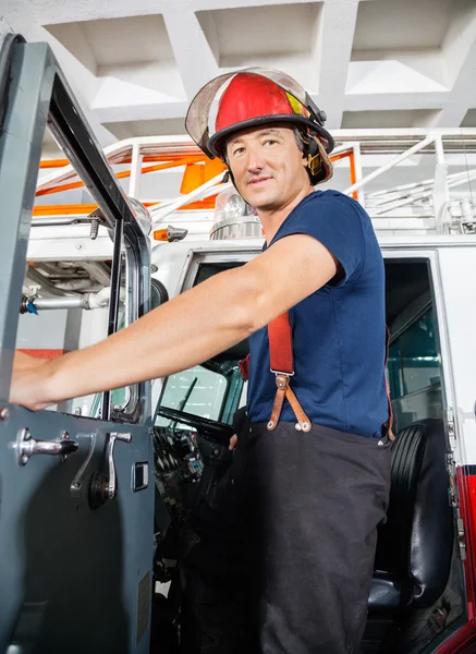 Sorridente pompiere in piedi su camion — Foto Stock