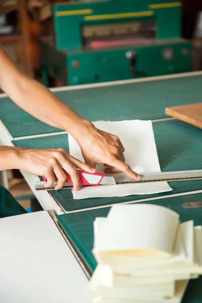 Женские руки резки бумаги с помощью лезвия на столе — стоковое фото