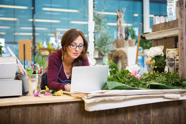 Florista usando laptop na loja de flores — Fotografia de Stock