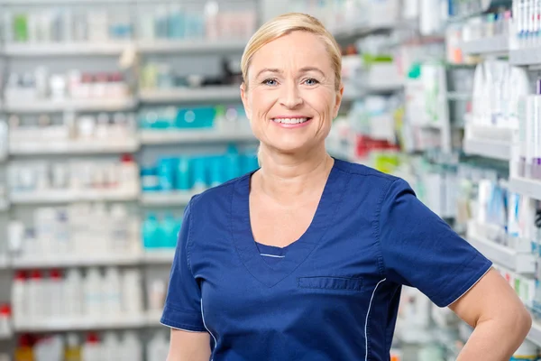 Sonriente química femenina de pie en la farmacia — Foto de Stock