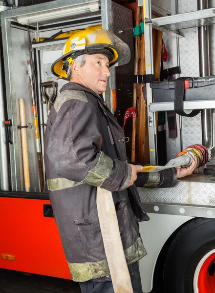 Brandweerman waterslang vaststelling In vrachtwagen bij brandweerkazerne — Stockfoto