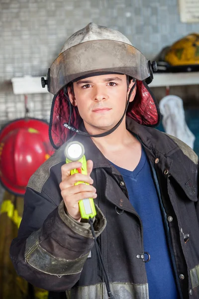 Уверенный пожарный держит факел на пожарной станции — стоковое фото