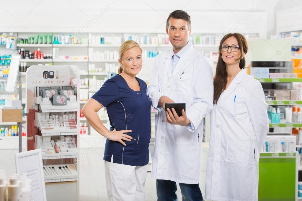 Confident Pharmacists With Digital Tablet Standing In Pharmacy