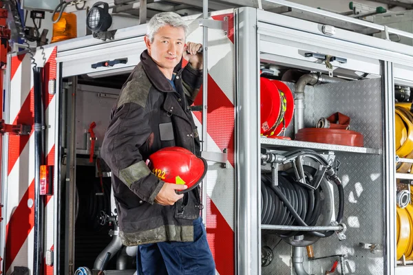 Bombeiro confiante em pé no carro de bombeiros — Fotografia de Stock