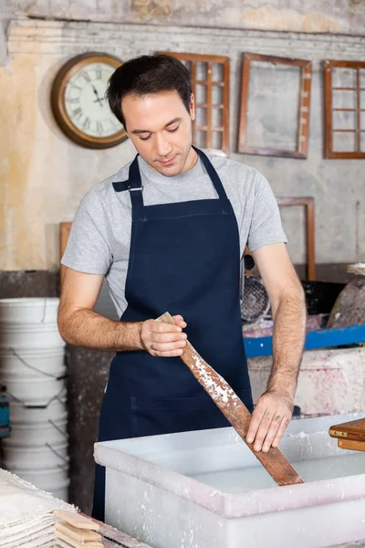 Lavoratore agitando polpa e acqua in fabbrica di carta — Foto Stock