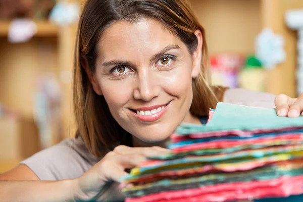 Vendedora sonriente con papeles coloridos en la tienda — Foto de Stock