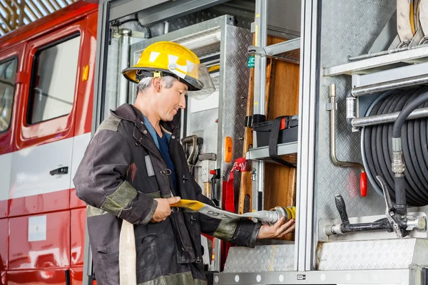 Feuerwehrmann fixiert Wasserschlauch in LKW am Feuerwehrhaus — Stockfoto