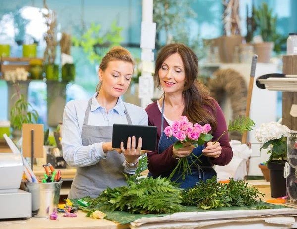Floristas usando tablet digital ao fazer buquê na loja — Fotografia de Stock