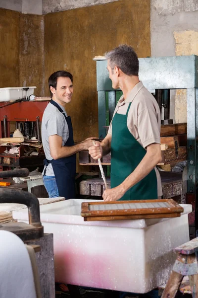 Werknemer kijken naar collega tijdens het gebruik van papier Press Machine — Stockfoto