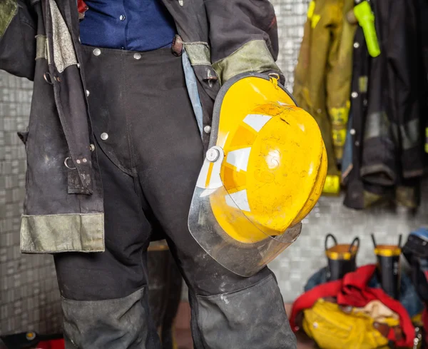Полуобнаженная пожарная держит каску на пожарной станции — стоковое фото