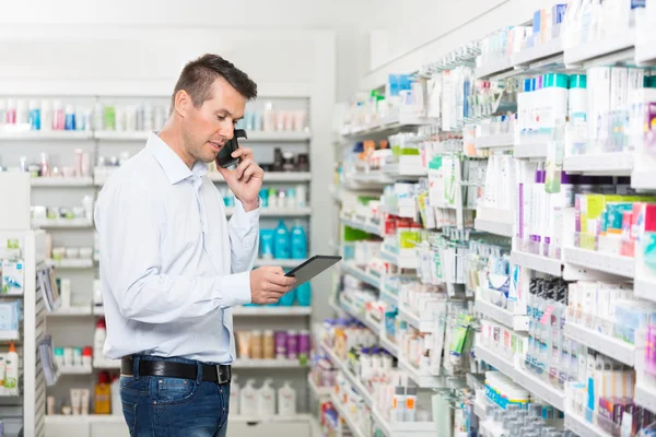 Cliente usando teléfono móvil y tableta digital en farmacia — Foto de Stock