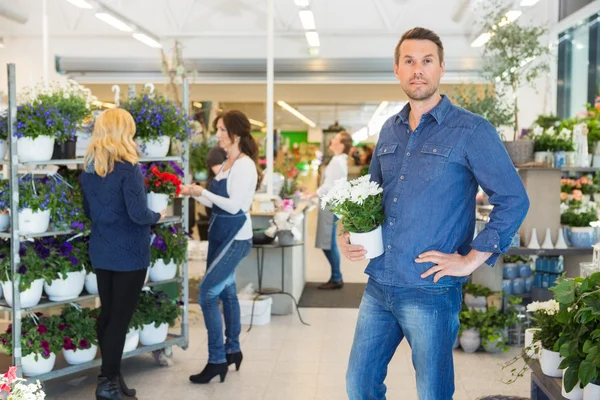 Retrato do homem que prende a planta do potenciômetro na loja da flor — Fotografia de Stock