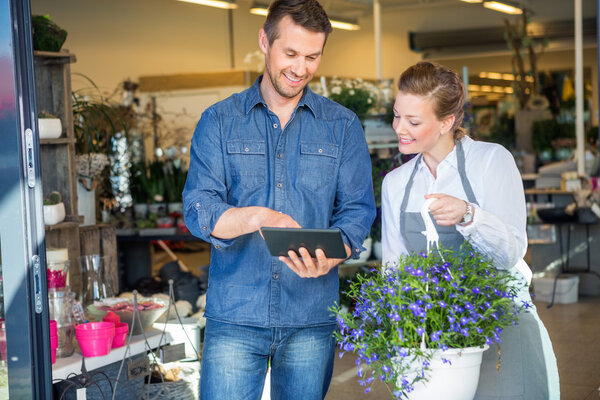 Customer Using Digital Tablet While Standing By Florist