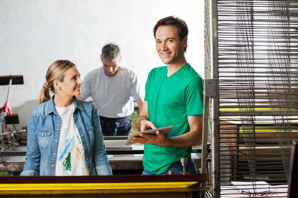 Vorgesetzter hält digitales Tablet in der Hand, während er mit Arbeitern im Büro steht — Stockfoto