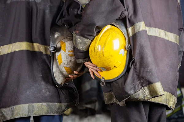 Lavoratori che tengono i caschi alla stazione dei pompieri — Foto Stock