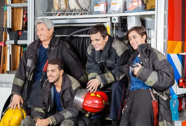 Команда счастливых пожарных на пожарной машине — стоковое фото