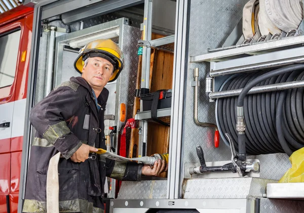 Brandweerman Looking Away terwijl vaststelling slang In Truck — Stockfoto