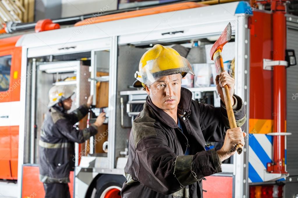 Confident Fireman Holding Axe Against Truck