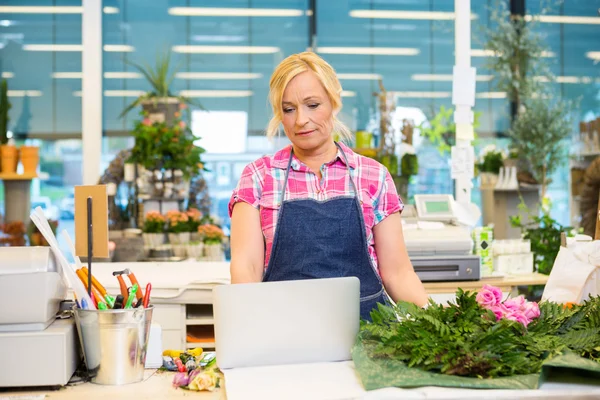 Florist med Laptop på disken i blomsteraffär — Stockfoto