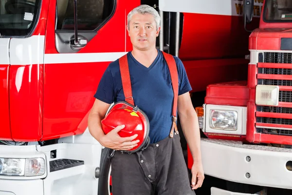Jistý hasič držící červená helma — Stock fotografie