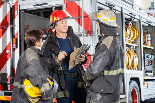 Firefighters Discussing Against Truck At Fire Station