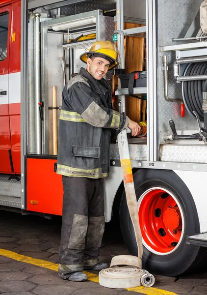 Lächelnder Feuerwehrmann justiert Schlauch im LKW — Stockfoto