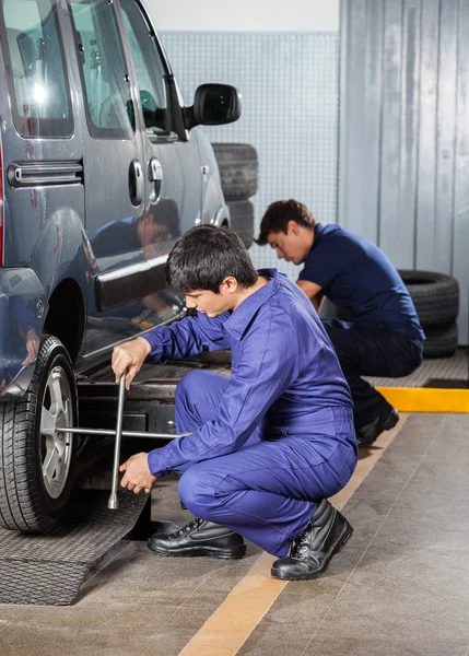 Tamirciler garajda araba lastiklerini tamir ediyor.