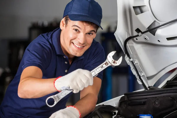 Happy Mechanic Holding Wrench While Examining Car Royalty Free Stock Images