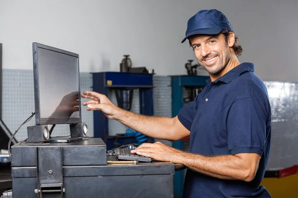 Mecánico feliz usando la computadora en taller de reparación — Foto de Stock