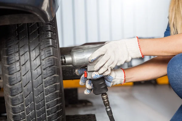 Mechanikerin benutzt Luftschlüssel, um Reifen zu fixieren — Stockfoto