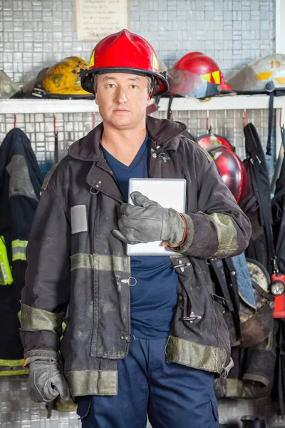 Selbstbewusster Feuerwehrmann mit digitalem Tablet am Feuerwehrhaus — Stockfoto