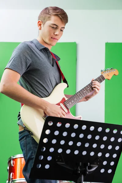 Guitarrista executando enquanto olha para notas musicais — Fotografia de Stock