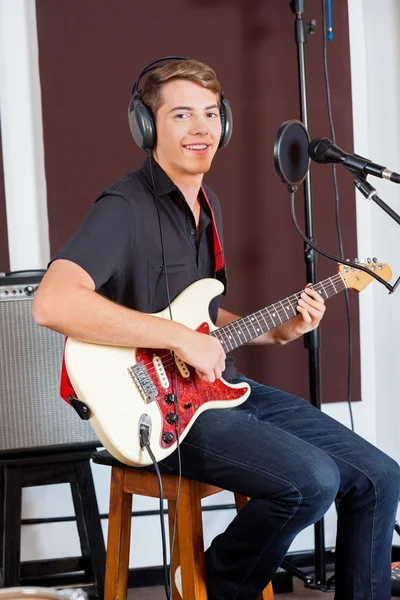 Sorridente cantante maschile che suona la chitarra in studio di registrazione — Foto Stock