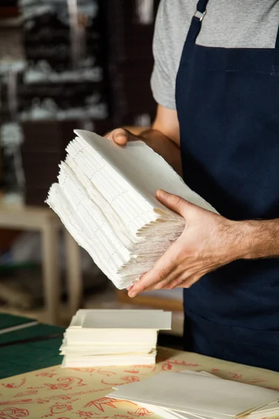 Мужской рабочий держит сложенные бумаги за столом — стоковое фото