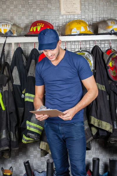 Brandweerman lezing Klembord op brandweerkazerne — Stockfoto