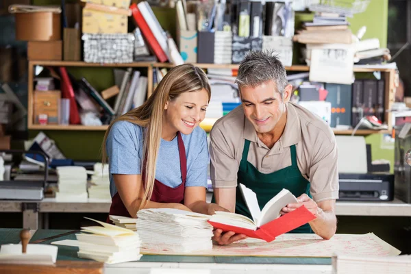 Travailleurs souriants analysant le carnet dans l'usine — Photo