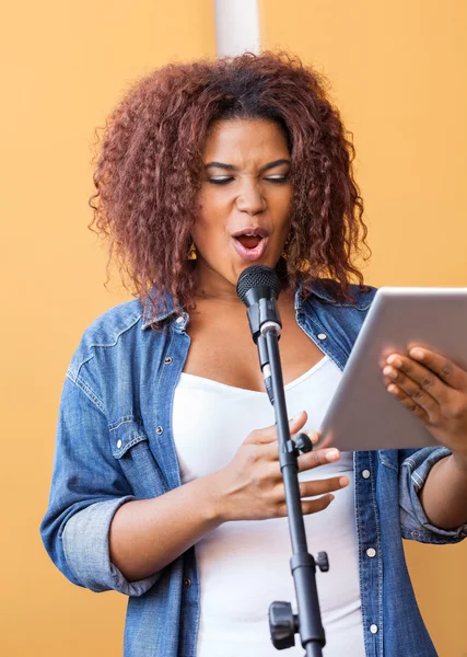 Zpěvačkou drží tabletový počítač při provádění ve studiu — Stock fotografie
