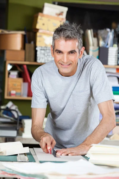 Fiducioso maturo lavoratore taglio carta a tavola — Foto Stock