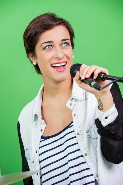 Jovem mulher cantando enquanto segurando microfone — Fotografia de Stock