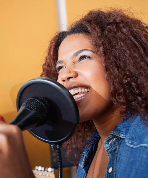 Mulher cantando enquanto segura microfone no estúdio de gravação — Fotografia de Stock