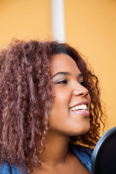 Mulher com cabelo encaracolado cantando no estúdio de gravação — Fotografia de Stock